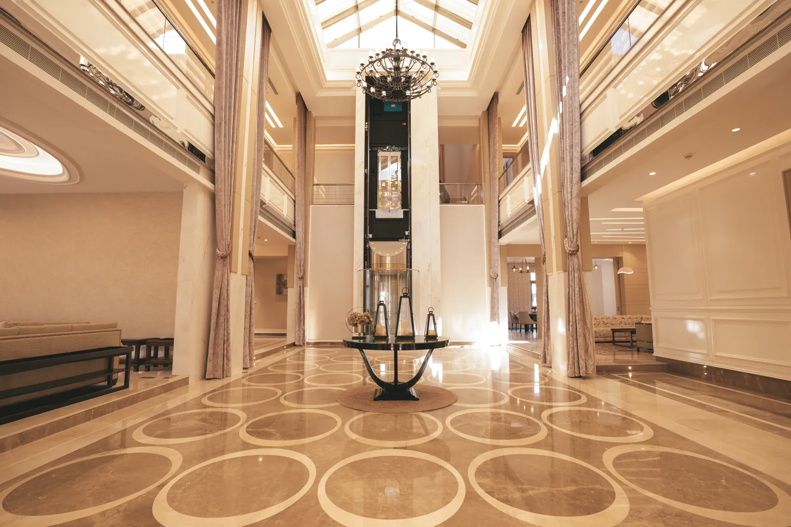 Atrium mit Glasdach, Kronleuchter und Marmorboden